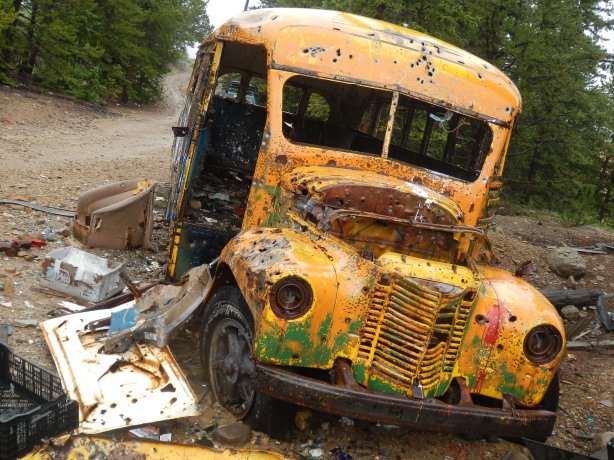 Old school bus shot full of holes near Stumptown above Leadville, surrounded by modern day garbage- an armchair, plastic milk crates, assorted TV guts and electronics...disgusting!